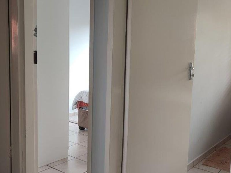 A view through a hallway showing access to multiple rooms with tiled flooring and standard interior doors.