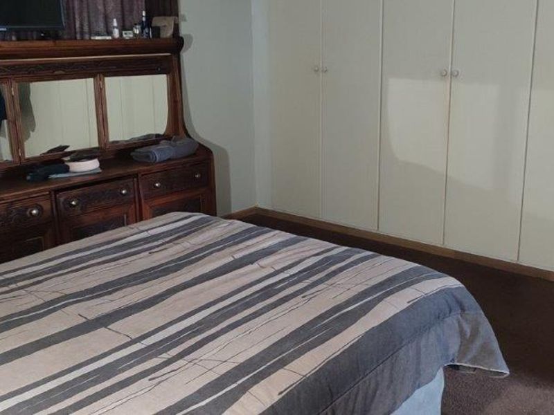 A bedroom featuring built-in floor-to-ceiling cupboards and carpeted flooring.