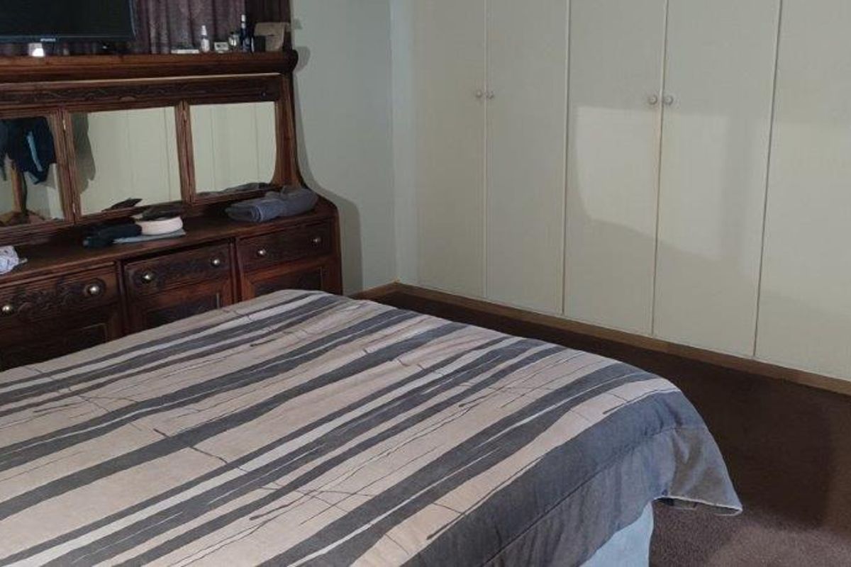 A bedroom featuring built-in floor-to-ceiling cupboards and carpeted flooring.