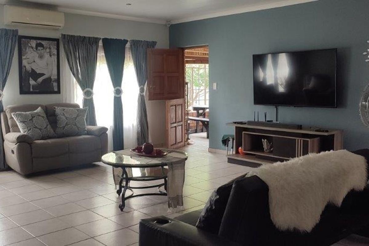Spacious living room featuring tiled flooring, a wall-mounted air conditioning unit, and direct access to an outdoor patio area.