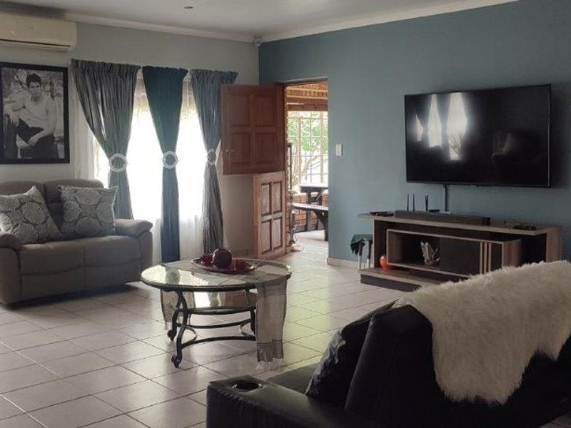 Spacious living room featuring tiled flooring, a wall-mounted air conditioning unit, and direct access to an outdoor patio area.