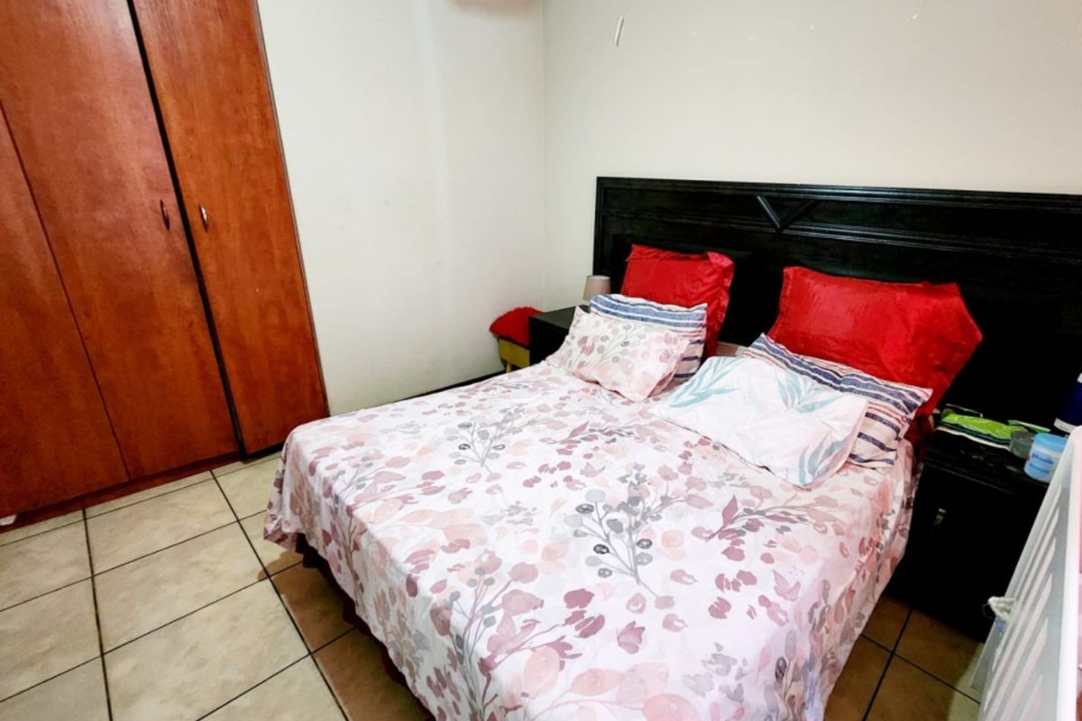 A bedroom featuring built-in wooden cupboards and tiled flooring.