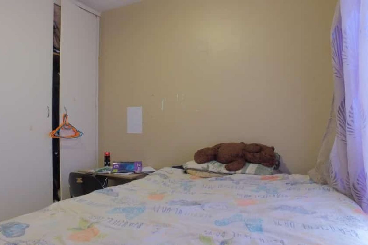 A compact bedroom featuring a built-in wardrobe with white doors and neutral wall finishes.