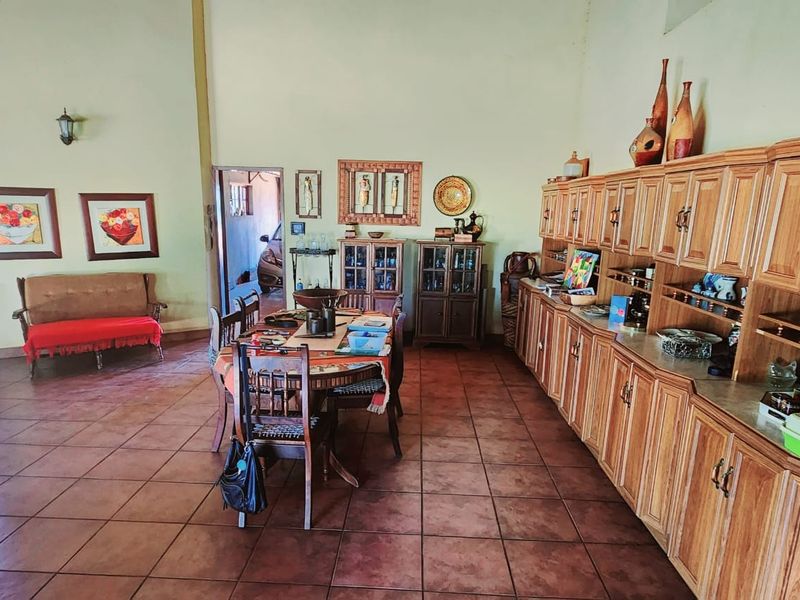 Spacious open-plan living and dining area featuring terracotta floor tiles and extensive built-in wooden cabinetry for storage.