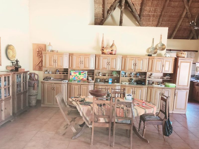 Spacious dining area featuring tiled flooring, extensive built-in wooden cabinetry, and a high vaulted thatched ceiling with exposed timber beams.
