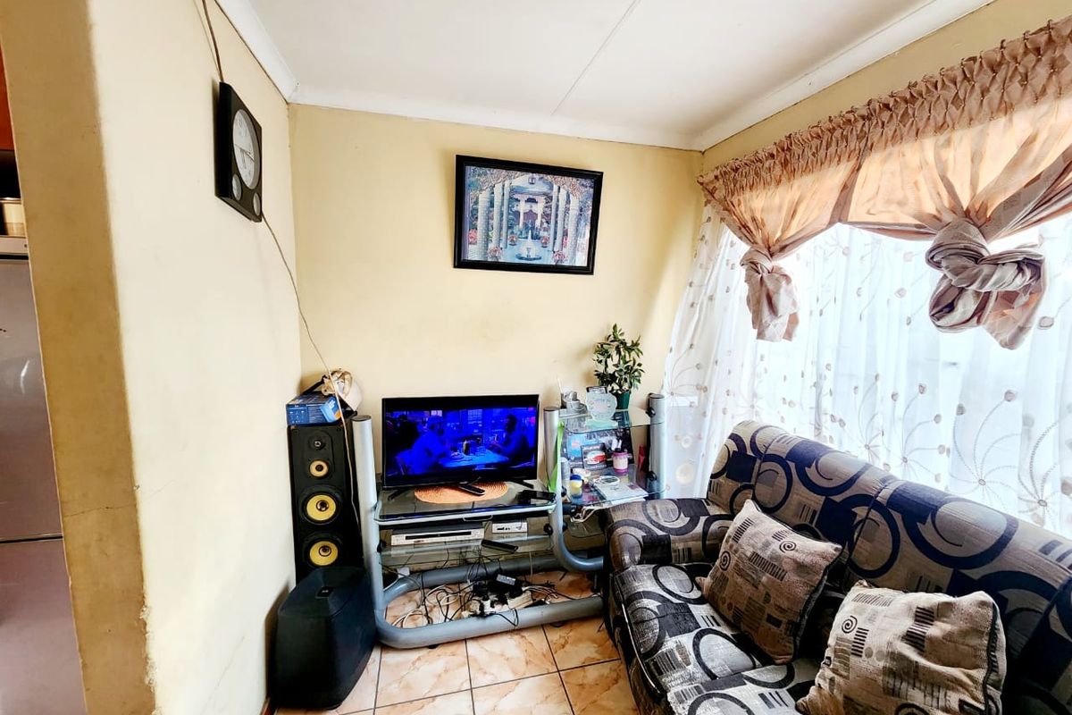 A compact living room featuring tiled flooring and coved ceilings, offering a functional space that could benefit from cosmetic updates and modern styling.