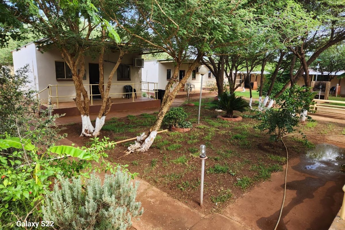 A view of the farm property featuring multiple detached units with covered porches set within a landscaped garden area with mature trees.