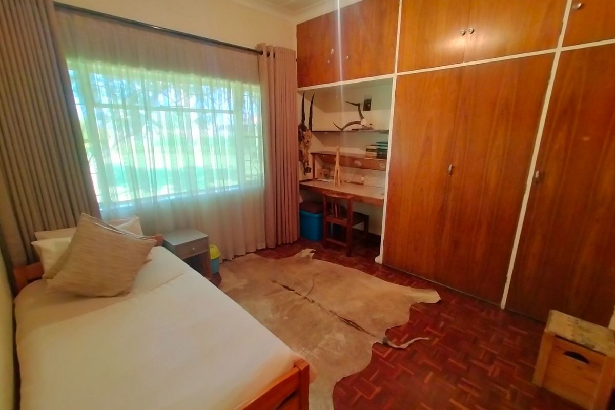 A bedroom featuring built-in wooden cupboards, a integrated desk area, and parquet flooring, offering a functional and classic layout.
