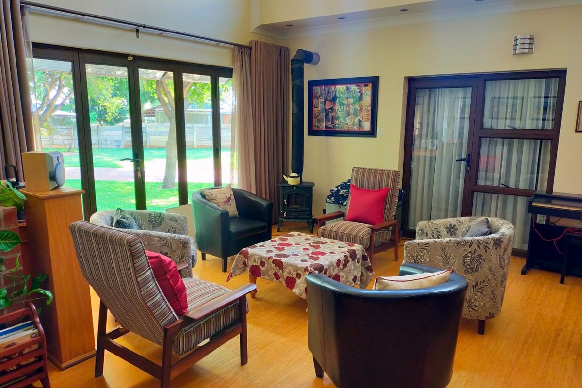 Spacious living room featuring high ceilings, wood-burning fireplace, and large glass sliding doors providing direct access to the garden.