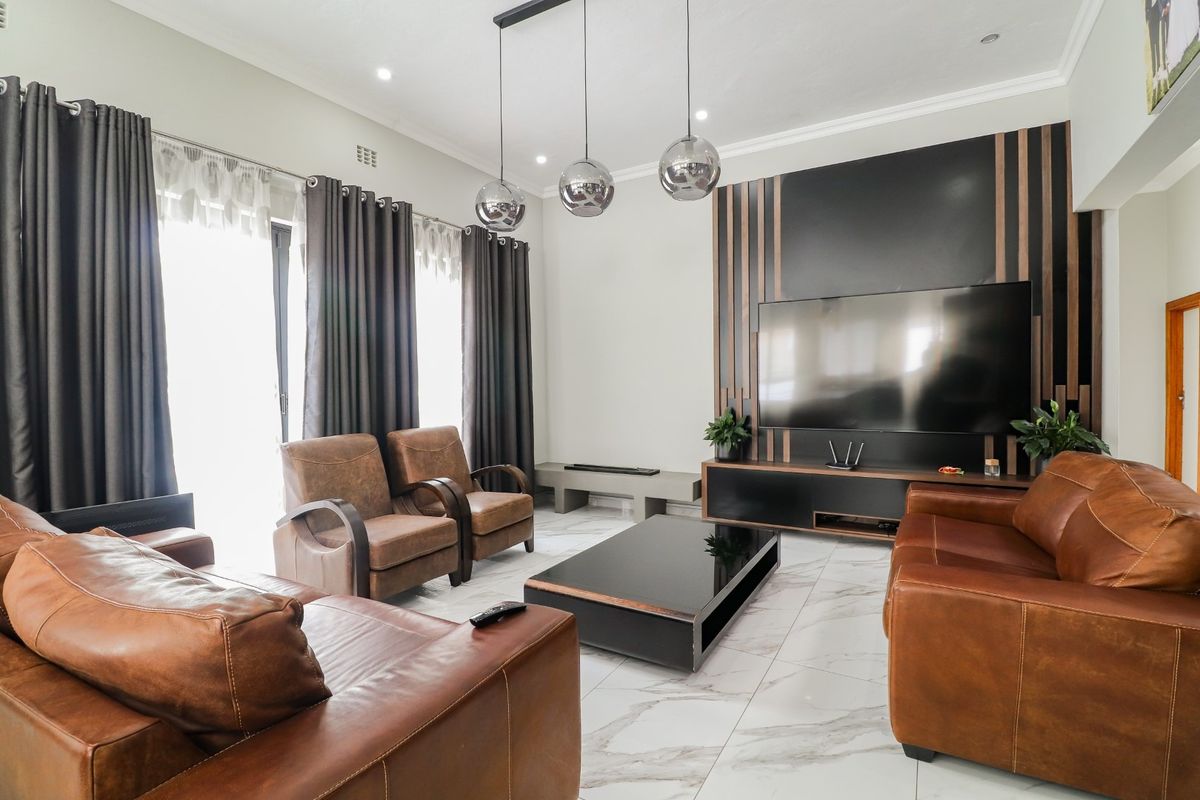 Modern living room featuring large format marble-look floor tiles, recessed downlighting, and a custom feature wall with integrated cabinetry.