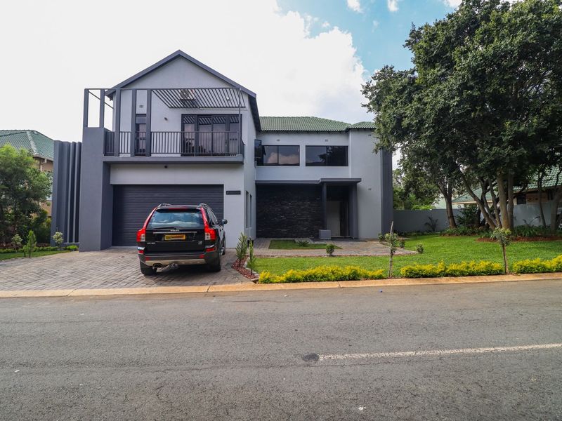 Modern double-story residential home featuring a paved driveway, integrated garage, balcony, and well-maintained front garden.
