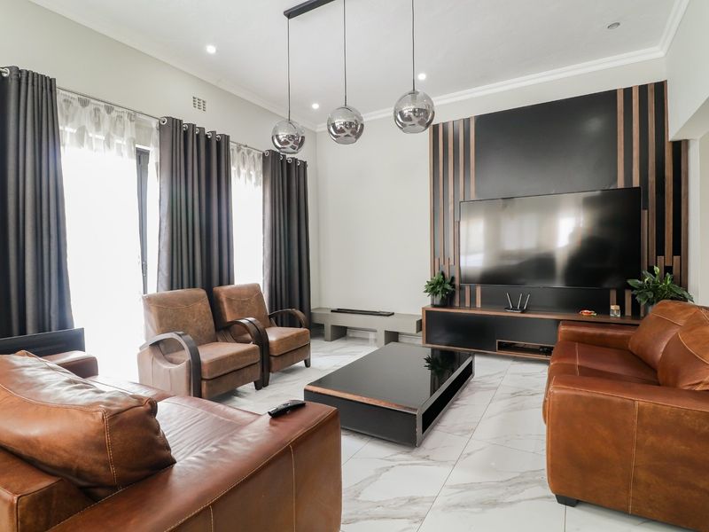 Modern living room featuring large format marble-look floor tiles, recessed downlighting, and a custom feature wall with integrated cabinetry.