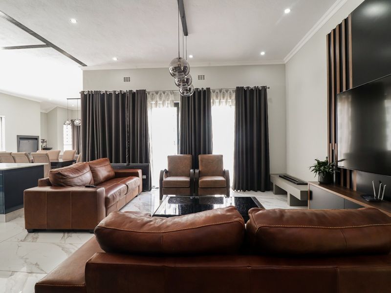 Spacious open-plan living area featuring modern marble-look floor tiles, recessed ceiling lighting, and a contemporary feature wall with integrated media cabinetry.