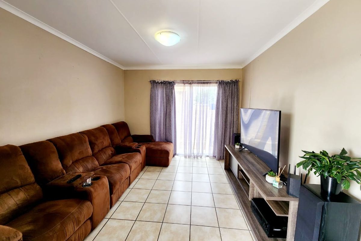 A functional living room featuring tiled flooring and sliding glass doors that provide access to the outdoor area.