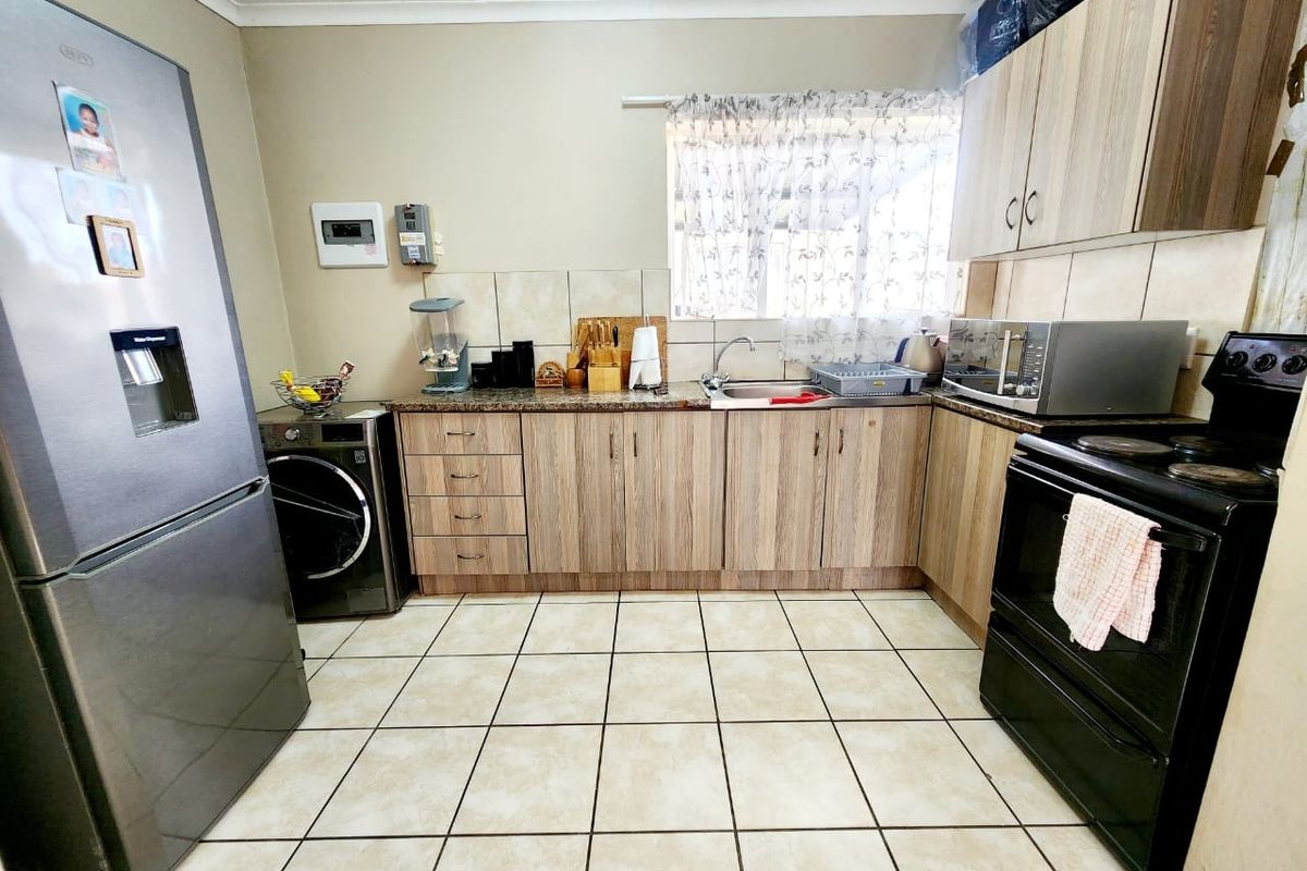 A functional kitchen featuring wood-look cabinetry, granite countertops, tiled flooring, and built-in appliances including a stove and sink.