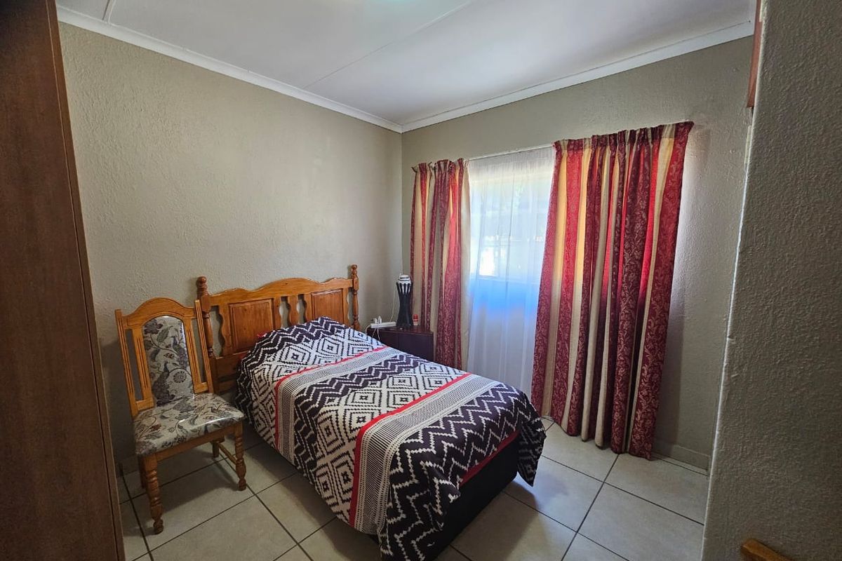 A functional bedroom featuring tiled flooring and a built-in cupboard, providing a simple and practical living space.