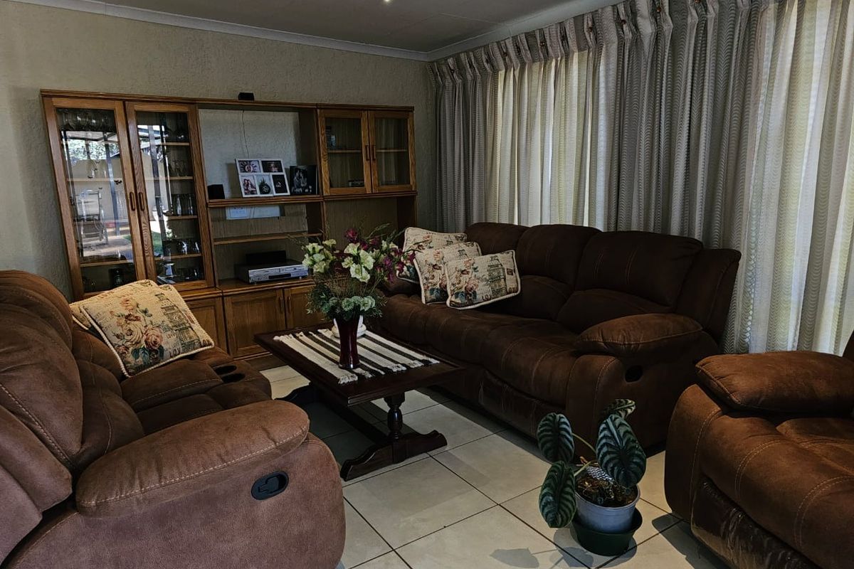 A comfortable living room featuring tiled flooring, recessed ceiling lighting, and a built-in wooden display cabinet.