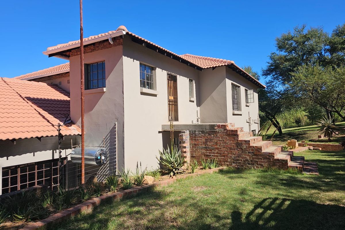 Rear exterior view of the farm property featuring a tiled roof, brick staircase, and established garden surroundings.