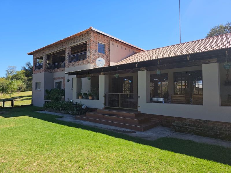 A view of the rear exterior of the farm property, featuring a covered patio area, brick and plaster facade, and a tiled roof.