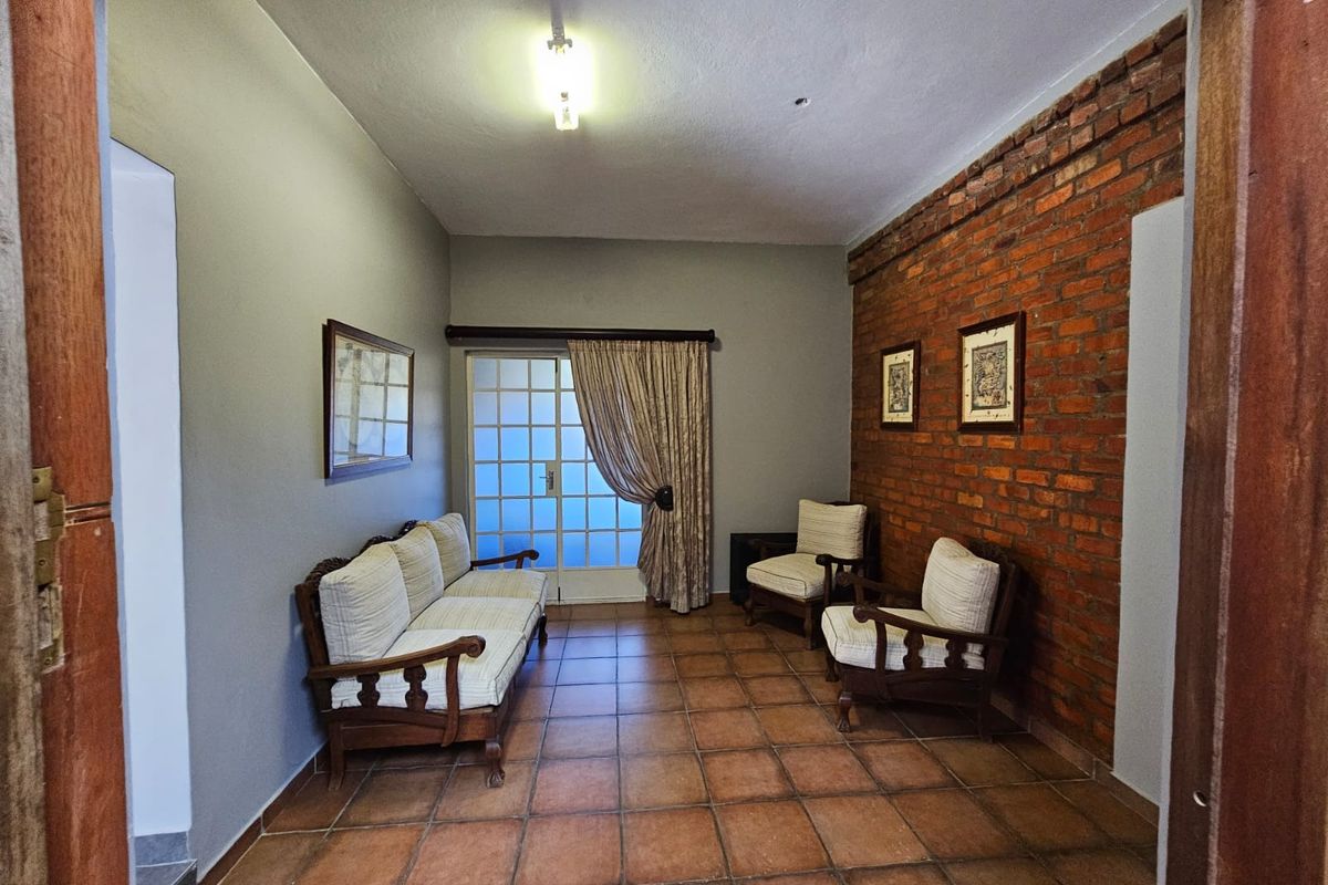 A cozy living area featuring a rustic exposed brick feature wall, terracotta floor tiles, and glass sliding doors leading to the exterior.