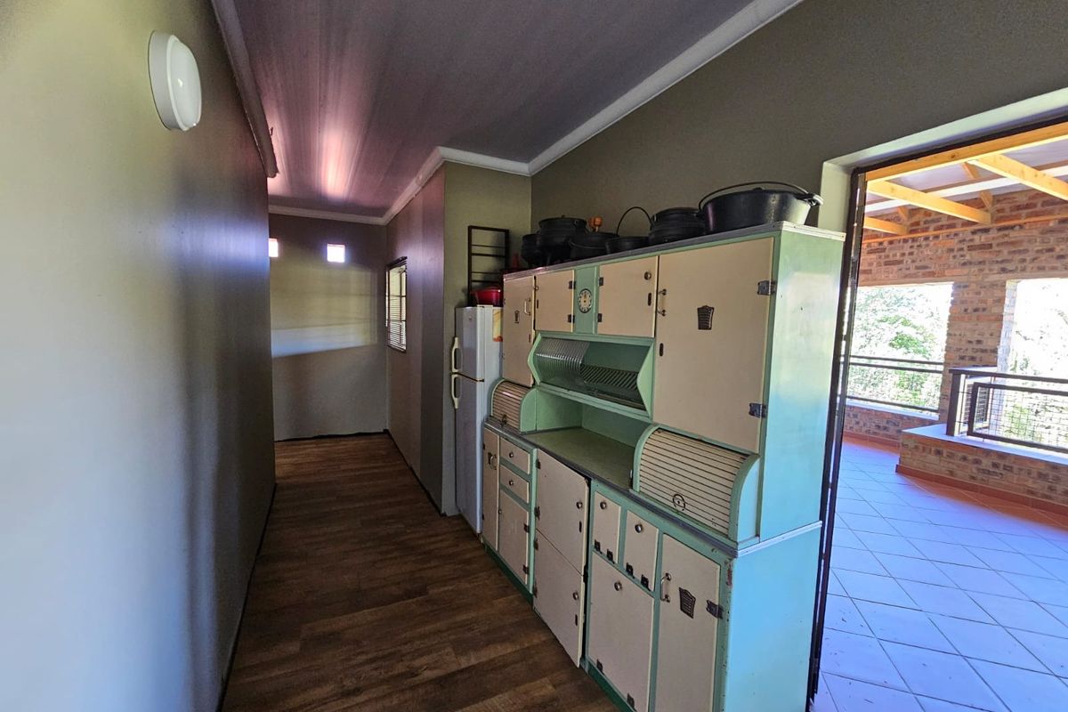 A functional kitchen area featuring vintage-style cabinetry and wood-look flooring, with direct access to an outdoor patio space.