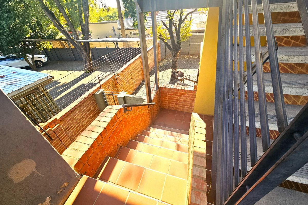 Exterior staircase with tiled steps, brick retaining walls, and metal railings leading down to the property grounds.