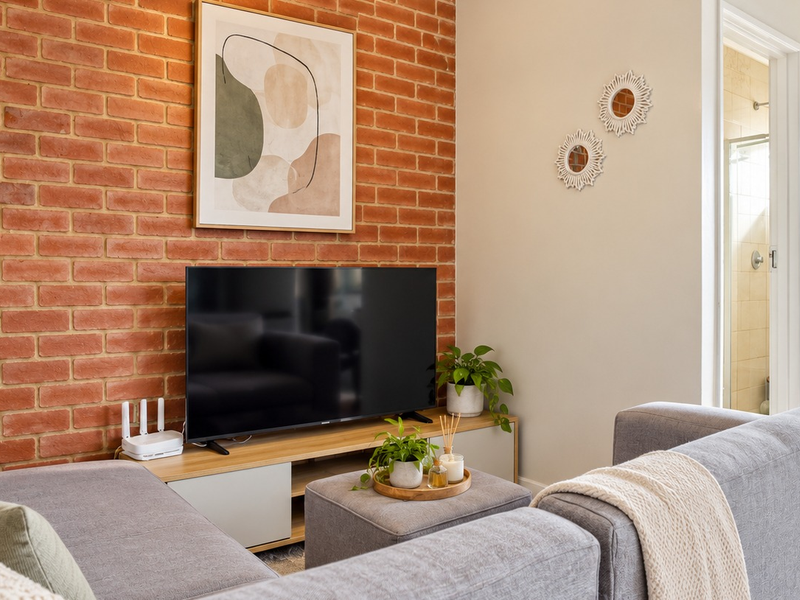 A cozy living room featuring a prominent exposed brick feature wall and direct access to an adjoining bathroom.