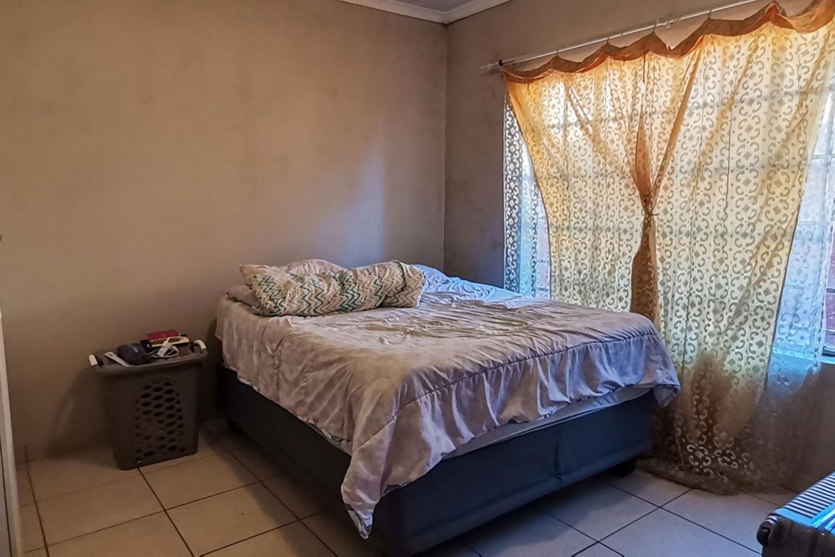 A bedroom featuring tiled flooring and a built-in cupboard, offering a functional space with natural light from the window.