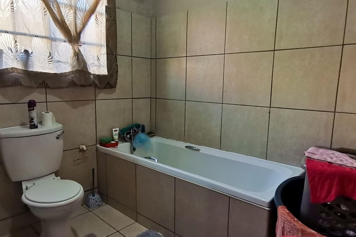 A functional bathroom featuring a built-in bathtub, tiled walls, and a standard toilet, offering a practical layout for daily use.