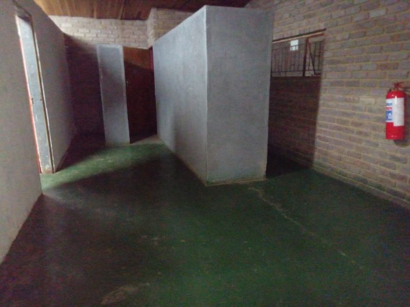 An unfinished utility space featuring exposed brick walls, a painted concrete floor, and a timber ceiling, suitable for storage or workshop conversion.