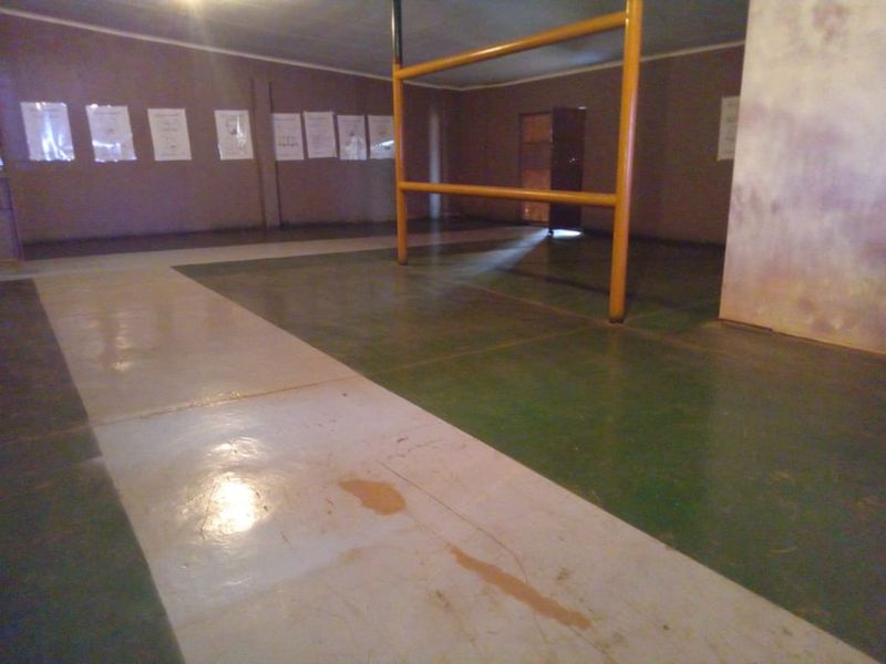 A large, open-plan utility or storage space featuring painted concrete flooring and a central structural steel support column.