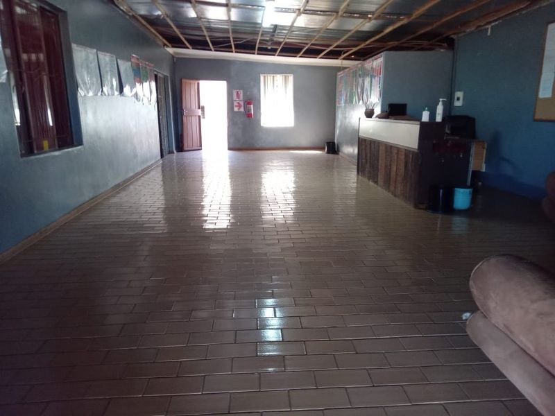 A large, open-plan utility or commercial space featuring tiled flooring, an exposed ceiling structure, and a built-in service counter.