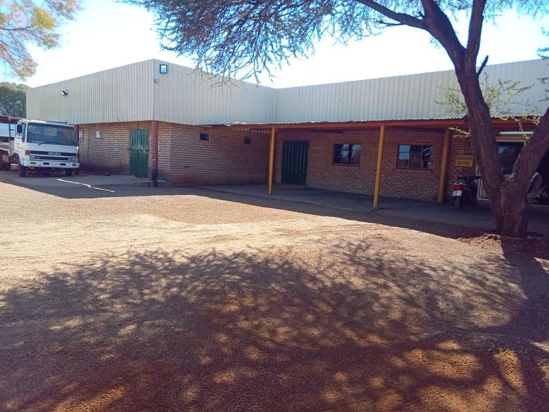 Front exterior view of a farm building featuring brick construction, corrugated metal roofing, and a covered walkway area.