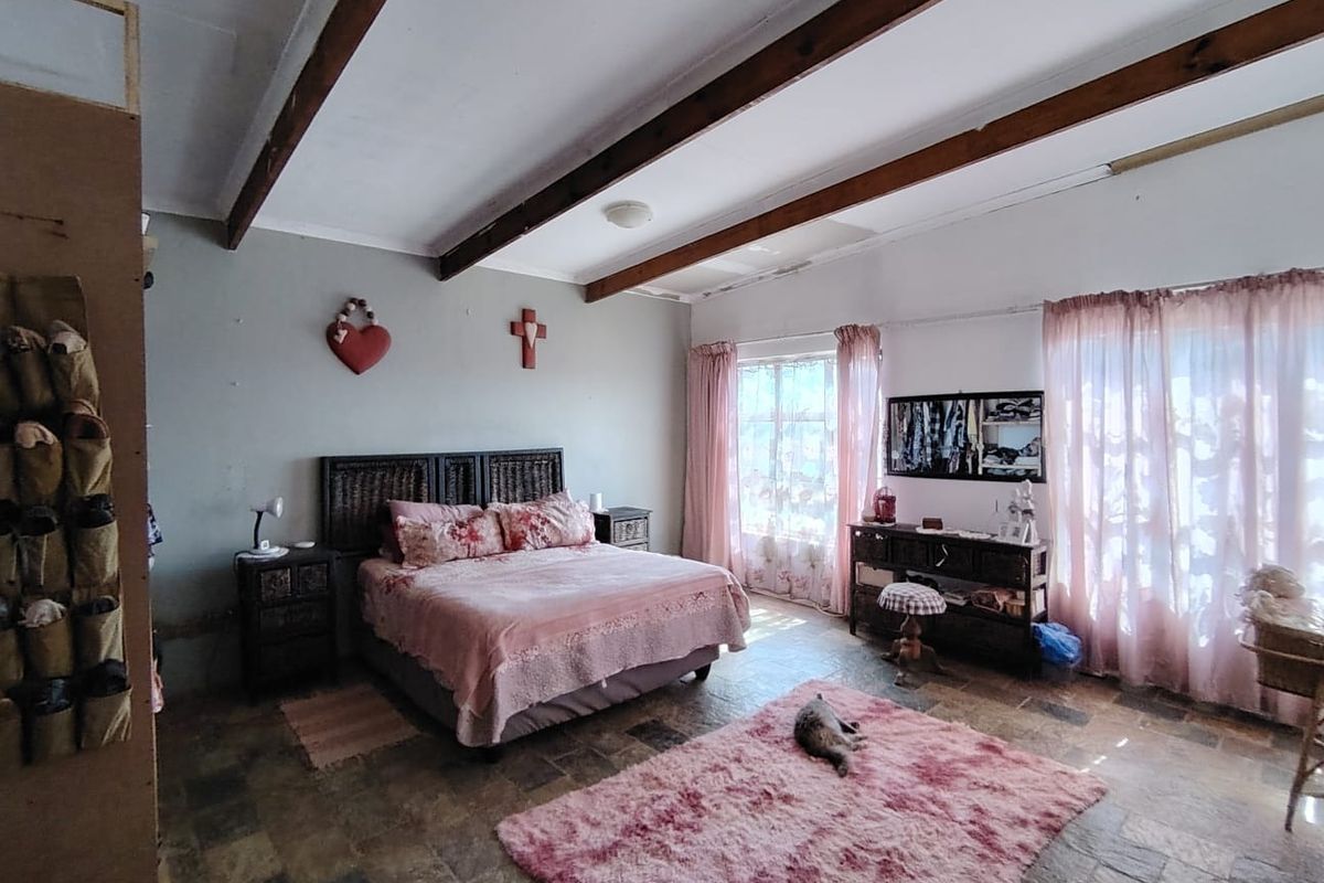 Spacious bedroom featuring exposed timber ceiling beams and natural stone flooring, with large windows providing ample natural light.