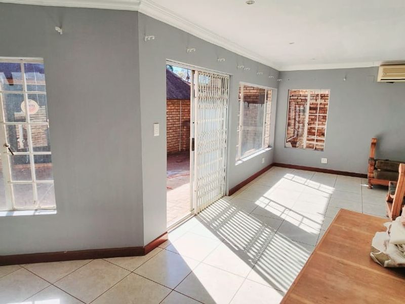 Spacious living area featuring tiled flooring, large windows, and a sliding door providing direct access to the outdoor patio area.