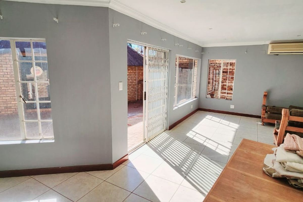 Spacious living area featuring tiled flooring, large windows, and a sliding door providing direct access to the outdoor patio area.