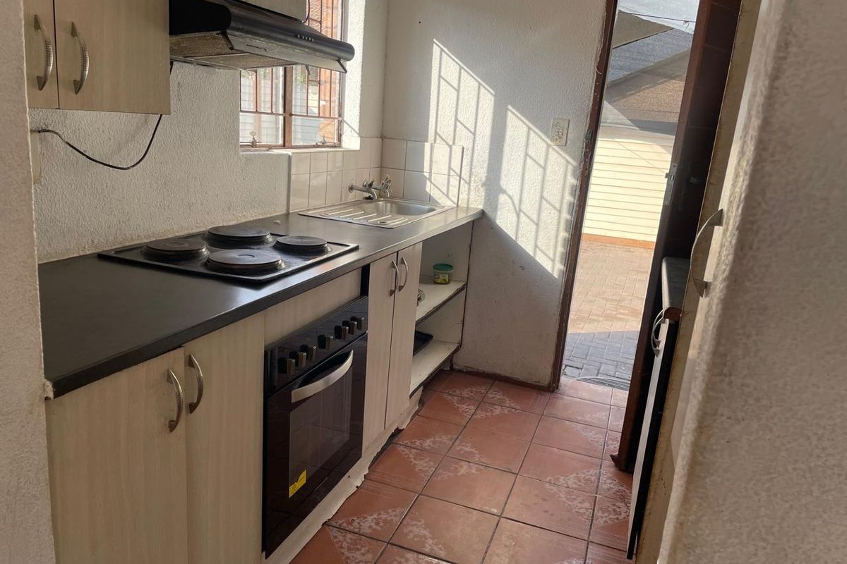 Compact kitchen featuring built-in cabinetry, electric hob, oven, extractor fan, and direct access to the rear exterior area.