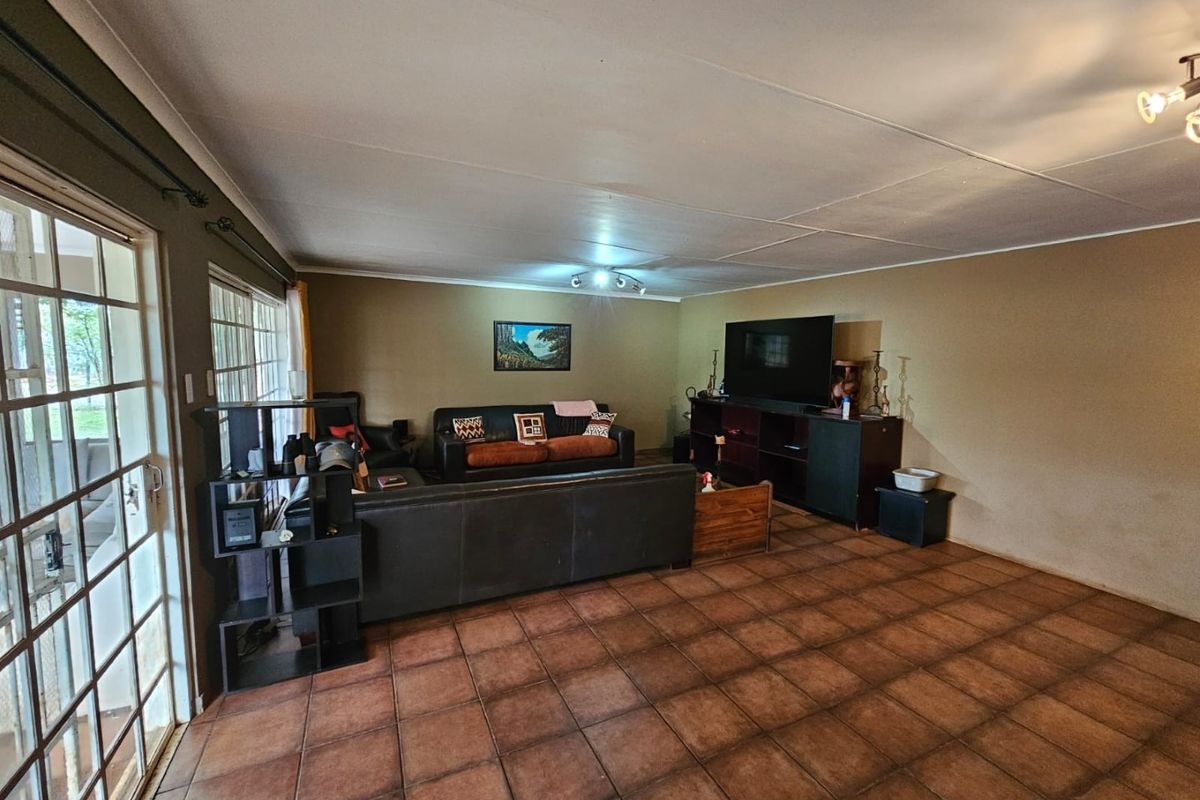 Spacious living room featuring large glass sliding doors, tiled flooring, and neutral wall tones, offering a comfortable and functional family living space.