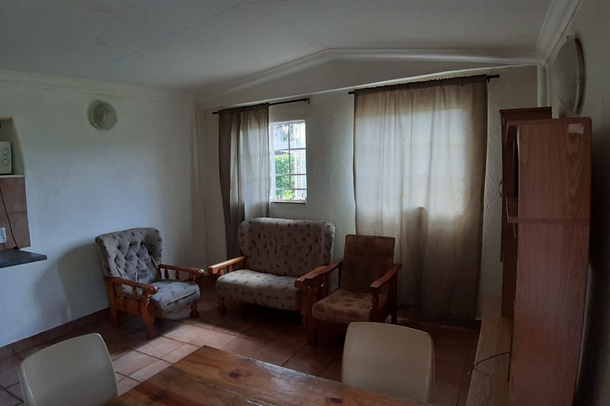 A modest living area featuring tiled flooring, built-in counter space, and natural light through window treatments.