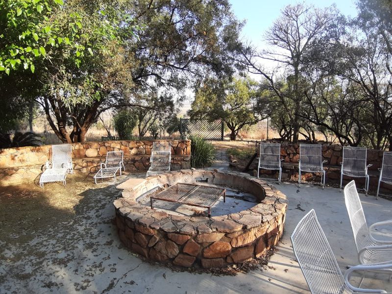 Outdoor entertainment area featuring a circular stone-built fire pit and integrated stone retaining walls set within a natural garden landscape.