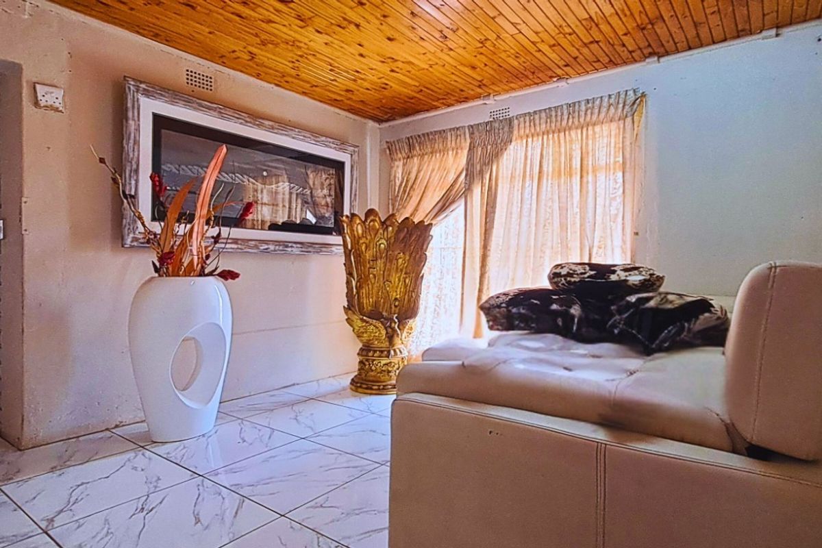 A living room featuring marble-look floor tiles and a timber-clad ceiling, providing a rustic aesthetic with access to an adjacent hallway.
