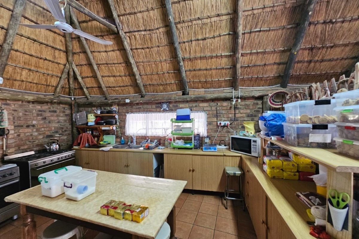 Rustic kitchen featuring exposed brick walls, a traditional thatched roof, wooden cabinetry, and a gas stove, offering a unique and character-filled cooking space.
