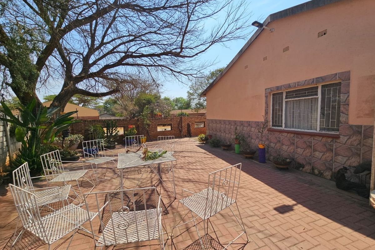 A spacious rear patio area featuring paved flooring, brick boundary walls, and direct access to the main house structure.