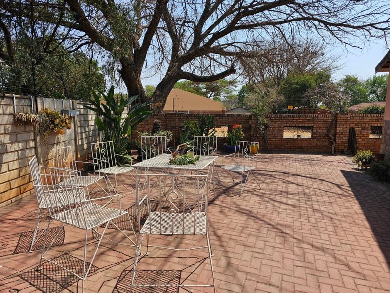 A paved outdoor patio area featuring a brick boundary wall and mature trees, providing a functional space for outdoor relaxation.