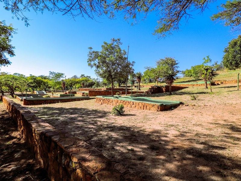 Outdoor recreational area featuring stone-walled garden beds and landscaped grounds with mature trees.