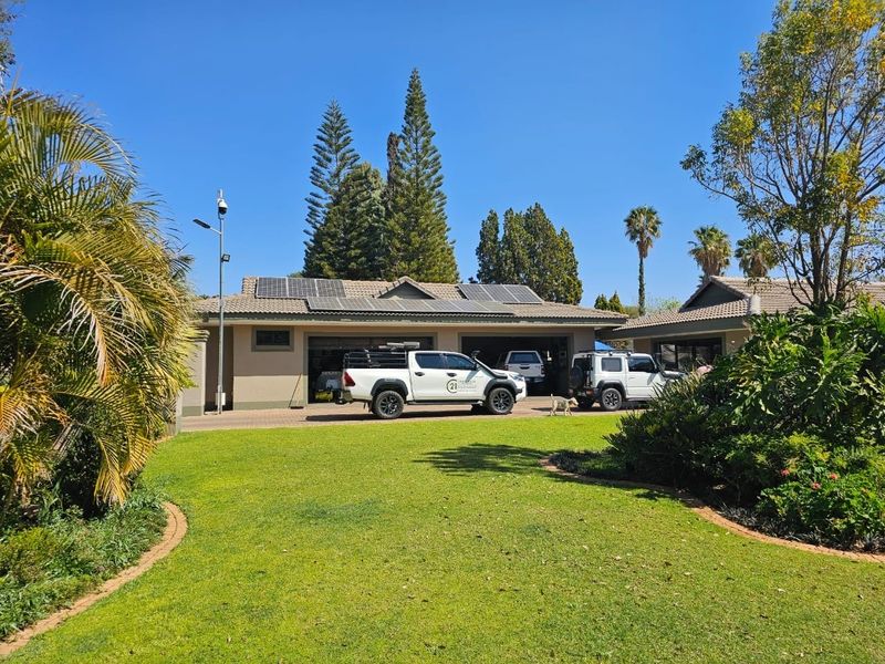 Front view of the property featuring a spacious driveway, landscaped garden, and a multi-car garage equipped with roof-mounted solar panels.
