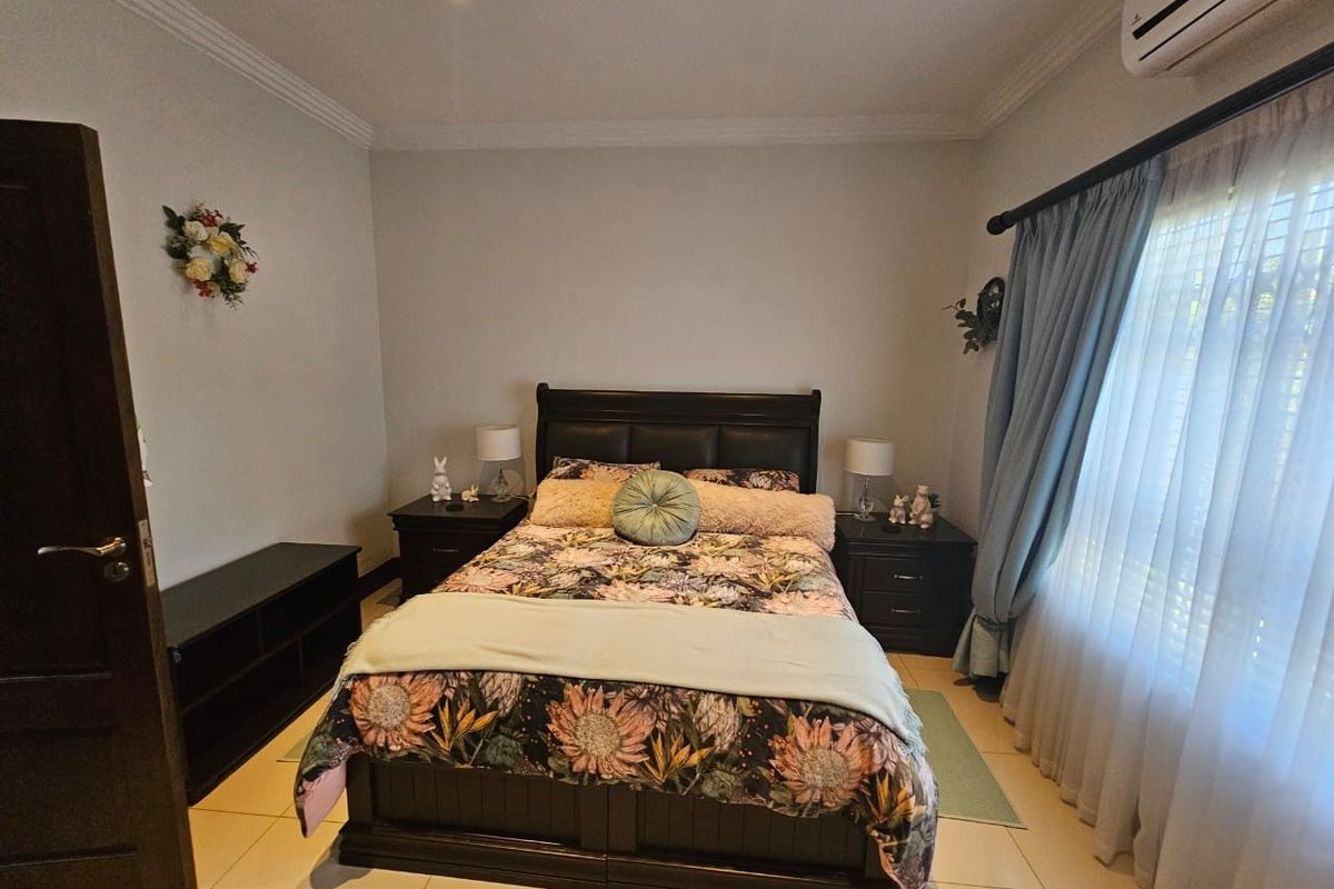 A well-maintained bedroom featuring tiled flooring, recessed ceiling lighting, and a wall-mounted air conditioning unit.