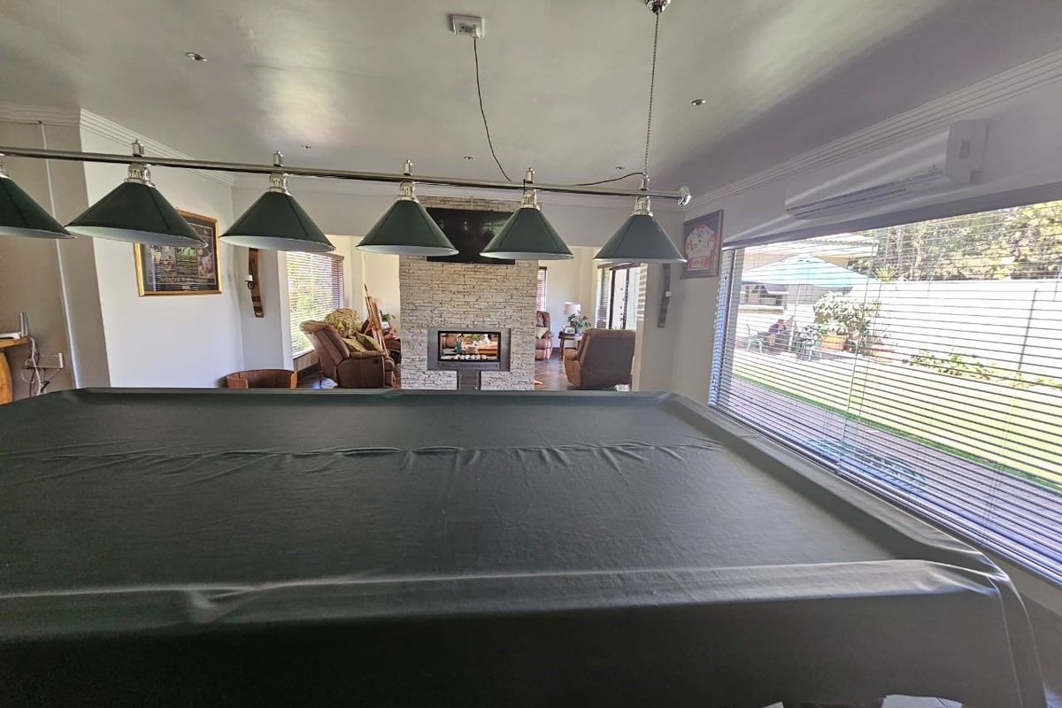 Spacious living area featuring a central stone-clad fireplace, split-system air conditioning, and large windows overlooking the garden.