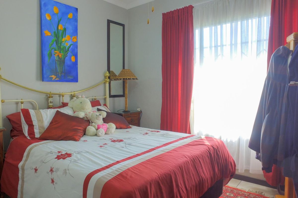 A well-lit bedroom featuring neutral wall finishes, tiled flooring, and a large window with curtain treatments.