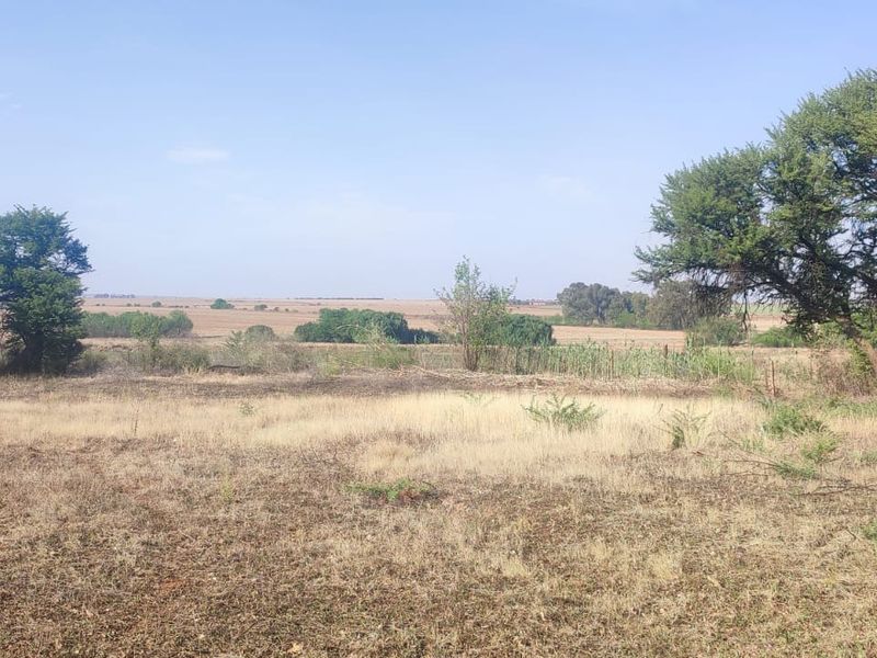 A wide-angle view of the vacant residential land, featuring natural vegetation, mature trees, and open landscape.